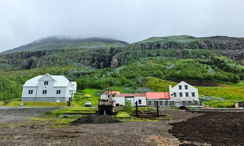 Houses by mountain against sky