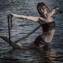 Full length of young woman with arms raised in sea