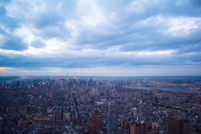 Aerial view of cityscape against cloudy sky