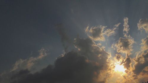 Low angle view of sunlight streaming through clouds