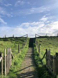 Wooden fence on field against sky