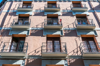 Low angle view of building facade with balconies and shadows