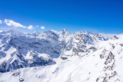 Scenic view of snowcapped mountains against blue sky