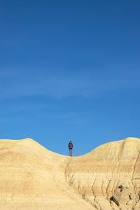 Front view of a woman on top of a hill standing with hands on pocket while looking to horizon