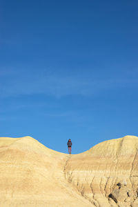 Rear view of man standing on desert against sky