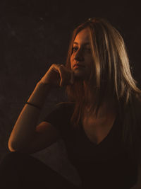 Portrait of beautiful young woman against black background