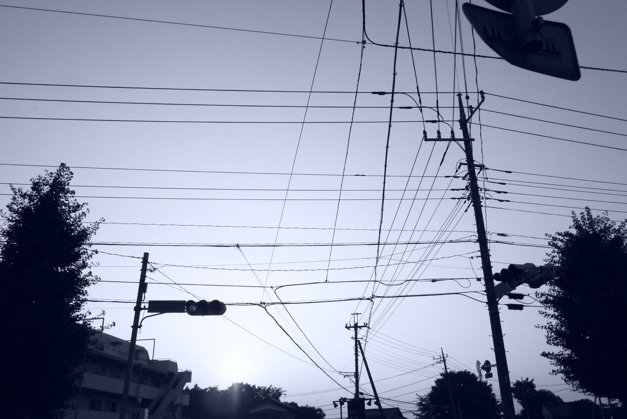 power line, electricity pylon, low angle view, cable, electricity, building exterior, power supply, built structure, architecture, silhouette, connection, sky, power cable, fuel and power generation, tree, technology, city, clear sky, street light, outdoors