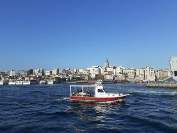 Boats in sea against clear blue sky