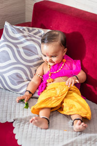 Portrait of cute girl sitting on sofa at home