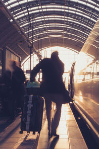 Rear view of people walking on railroad station platform