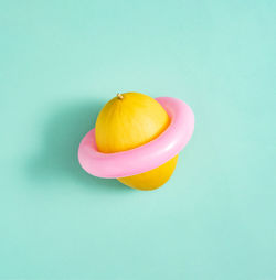 Yellow honeydew melon with pink swimming ring isolated on green background. abstract. 