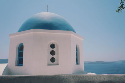 Greek church by sea against clear sky