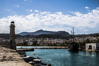 Boats moored at harbor against cloudy sky