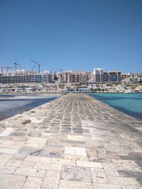 View of city buildings against clear blue sky