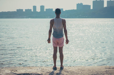 Rear view of man standing in front of sea