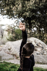 Side view of woman with arm raised exercising in park