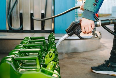 Person filling oil canisters at gas station. fuel crisis concept