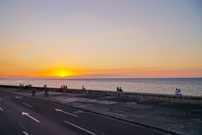 People on promenade against sky during sunset