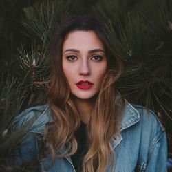 Portrait of beautiful young woman against plants