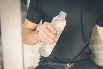 Midsection of man holding  bottle of water 