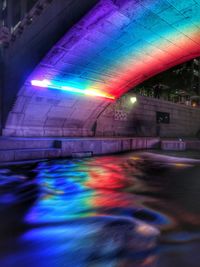 Multi colored illuminated bridge in city at night