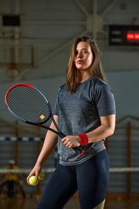 Portrait of young woman standing against wall