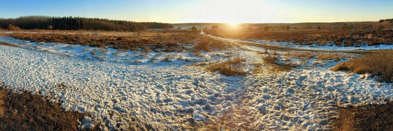 Surface level of snowy land against sky during sunset