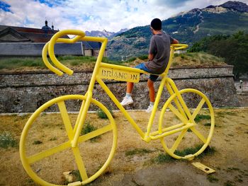 Rear view of man standing by bicycle