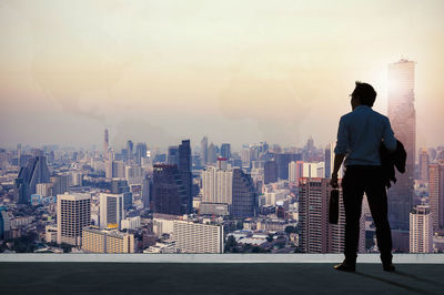 Rear view of man standing by buildings against sky