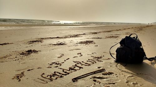 Text on sand at beach against sky