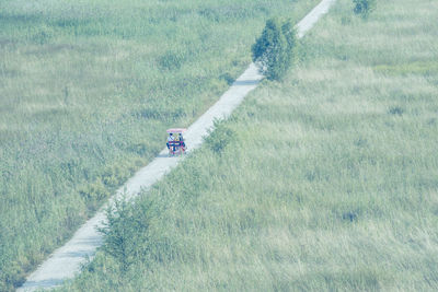 High angle view of people riding vehicle on road amidst grassy field