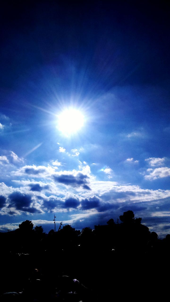 silhouette, sun, blue, low angle view, sky, scenics, tranquil scene, beauty in nature, tranquility, nature, outline, lens flare, sunbeam, cloud - sky, sunny, day, mountain, outdoors, bright, majestic, no people, non-urban scene, tourism