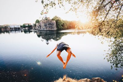 Man jumping against lake