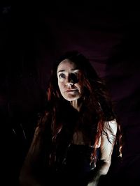 Close-up of young woman against black background