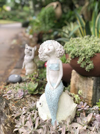 Close-up of statue against plants in yard