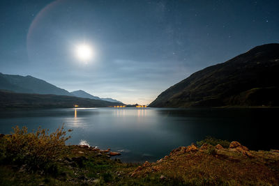 Scenic view of lake and mountains against sky at night