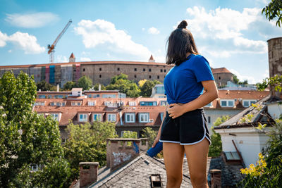 Rear view of woman standing against buildings in city