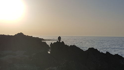 Silhouette man on beach against sky during sunset