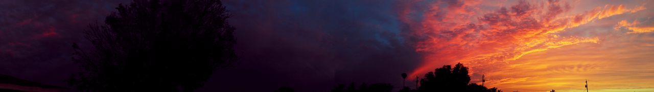 Silhouette of trees against dramatic sky at sunset