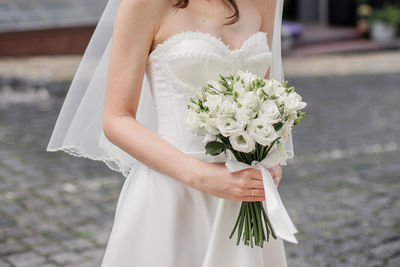 Midsection of bride holding bouquet