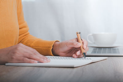 Midsection of woman using mobile phone while sitting on table