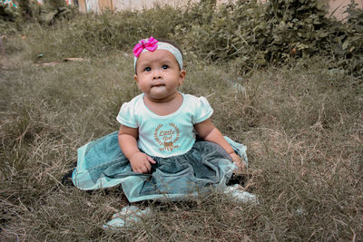 Cute baby girl sitting on land