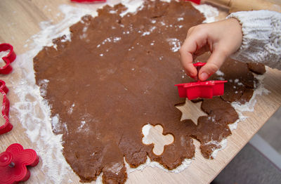 Child making christmas cookies from gingerbread dough and cookie cutters