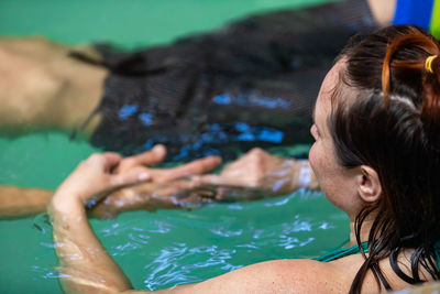 High angle view of women holding hands standing in swimming pool