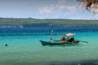 Fishing boat on blue sea against blue sky