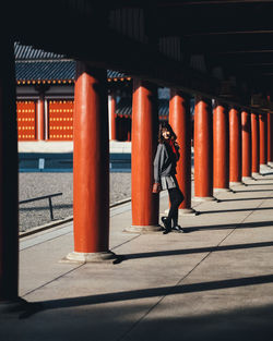 Full length of woman standing by columns in corridor