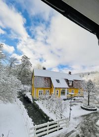 Snow covered houses by building against sky