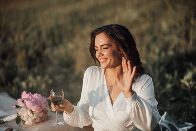 Young woman smiling while sitting on glass against blurred background