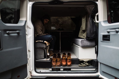 Side view of calm male traveler sitting in parked van and resting on cloudy day