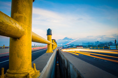 Road by bridge in city against sky